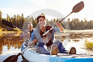 Male Gay Couple Rowing Kayak On Lake Together