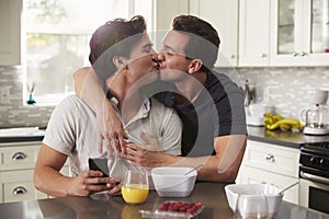 Male gay couple in their 20s kissing in their kitchen