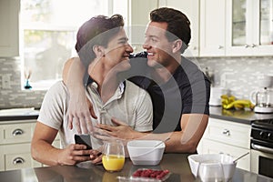 Male gay couple in their 20s embracing in their kitchen