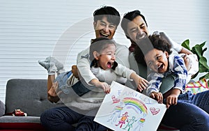 Male gay taking care adopted children who are happy diverse little Caucasian girl and African boy, playing with fun, drawing
