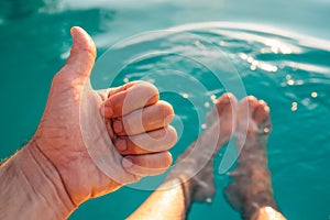 Male giving thumb up by outdoor swimming pool