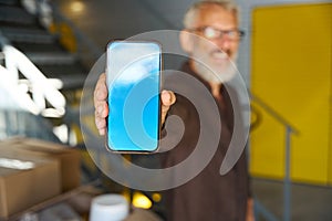 Male in glasses with mobile phone in a warehouse