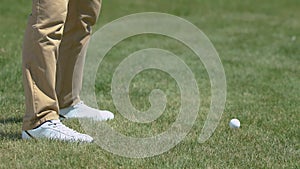 Male golf player making shot with iron club, practicing in country golf club