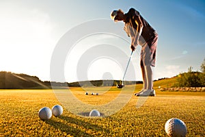 Male golf player practicing a par during sunset