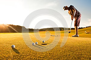 Male golf player practicing a par during sunset