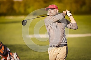 Male golf player teeing off with club.