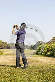 Male golf player teeing off golf ball from tee box