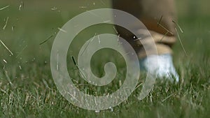 Male golfer hitting ball with driver playing golf on course, slow-motion closeup