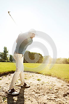 Male golfer hitting ball out of a sand trap