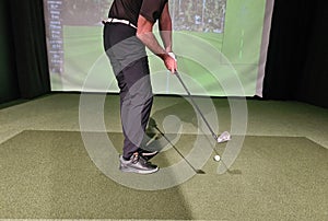 Male golfer holding club playing golf indoors