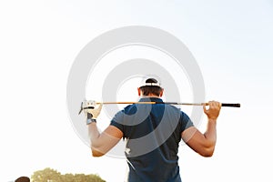 Male golfer holding driver while standing on green course