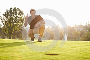 Male Golfer Lining Up Putt On Green