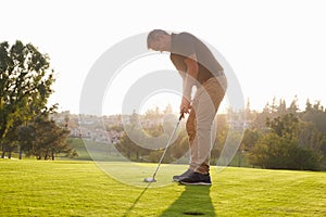 Male Golfer Lining Up Putt On Green