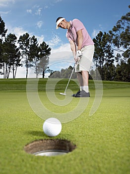 Male Golfer Putting Ball On Green