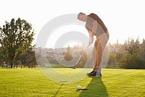 Male Golfer Putting Ball Into Hole On Green