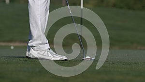 Male golfer putting a golf ball in to hole