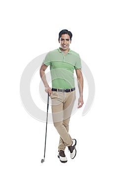 Male golfer standing with a golf club and smiling