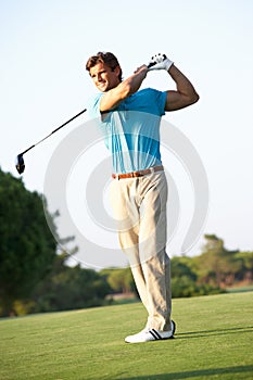 Male Golfer Teeing Off On Golf Course photo
