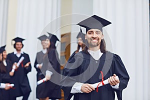 Male graduate is smiling against the background of university graduates.