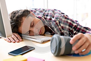 Male graphic designer sleeping on desk in a modern office