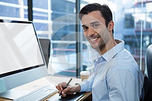 Male graphic designer using graphics tablet at desk