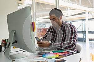 Male Graphic designer using mobile phone at desk