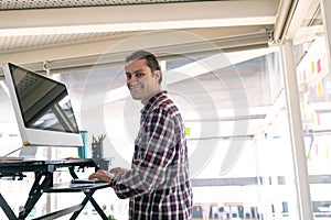 Male graphic designer working on computer at desk in office