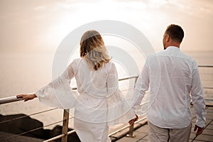 Male groom and female bride walking on the bridge holding hands