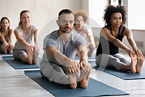 Male with group of diverse people practicing Seated Forward Bend