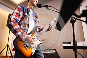 a male guitarist plays an electric guitar during rehearsal with his band