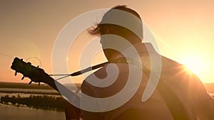 Male guitarist sitting near water outdoors and playing acoustic guitar