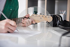 Male guitarist touching strings while drawing notes