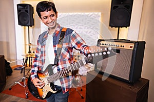 a male guitarist tunes the strings of an electric guitar before playing