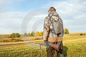 Male with a gun walking at field
