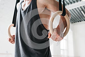 Male gymnast doing workout on gymnastics rings in cross gym