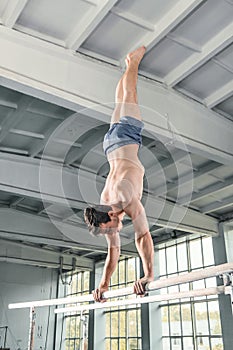 Male gymnast performing handstand on parallel bars