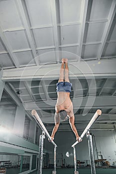 Male gymnast performing handstand on parallel bars