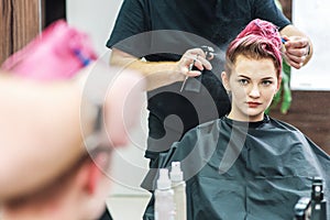Male hairdresser applying water spray on female client`s hair.