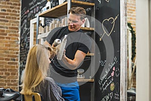 Male hairdresser blowdrying long wet hair of a woman