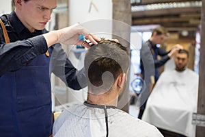 Male hairdresser cutting hair at barbershop