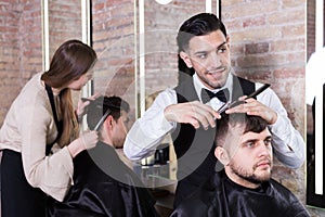 Male hairdresser cutting hair of male client