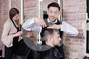 Male hairdresser cutting hair of male client