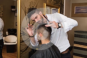 Male Hairdresser Cutting Hair Of Smiling Man Client