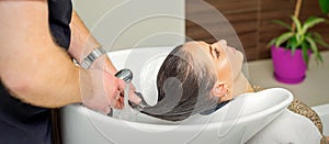 Hairdresser rinses hair of woman photo