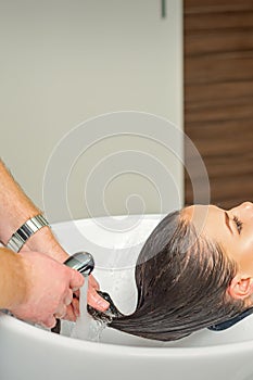 Hairdresser rinses hair of woman photo