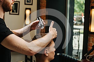 Male hairdresser sprinkling young man`s hair with talc in a barber shop