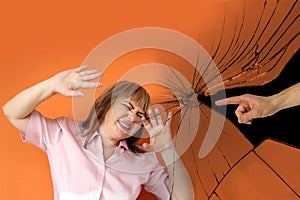 Male hand against a background of broken glass shows an accusing gesture at a woman who threw up her hands in despair,