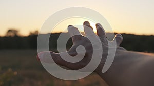 Male Hand against Sunset. Touch the Sun. Sun Shines through fingers. Slow motion