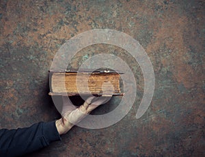 Male hand with antique book on grunge background