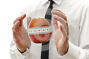 Male hand around apple wrapped with measuring tape